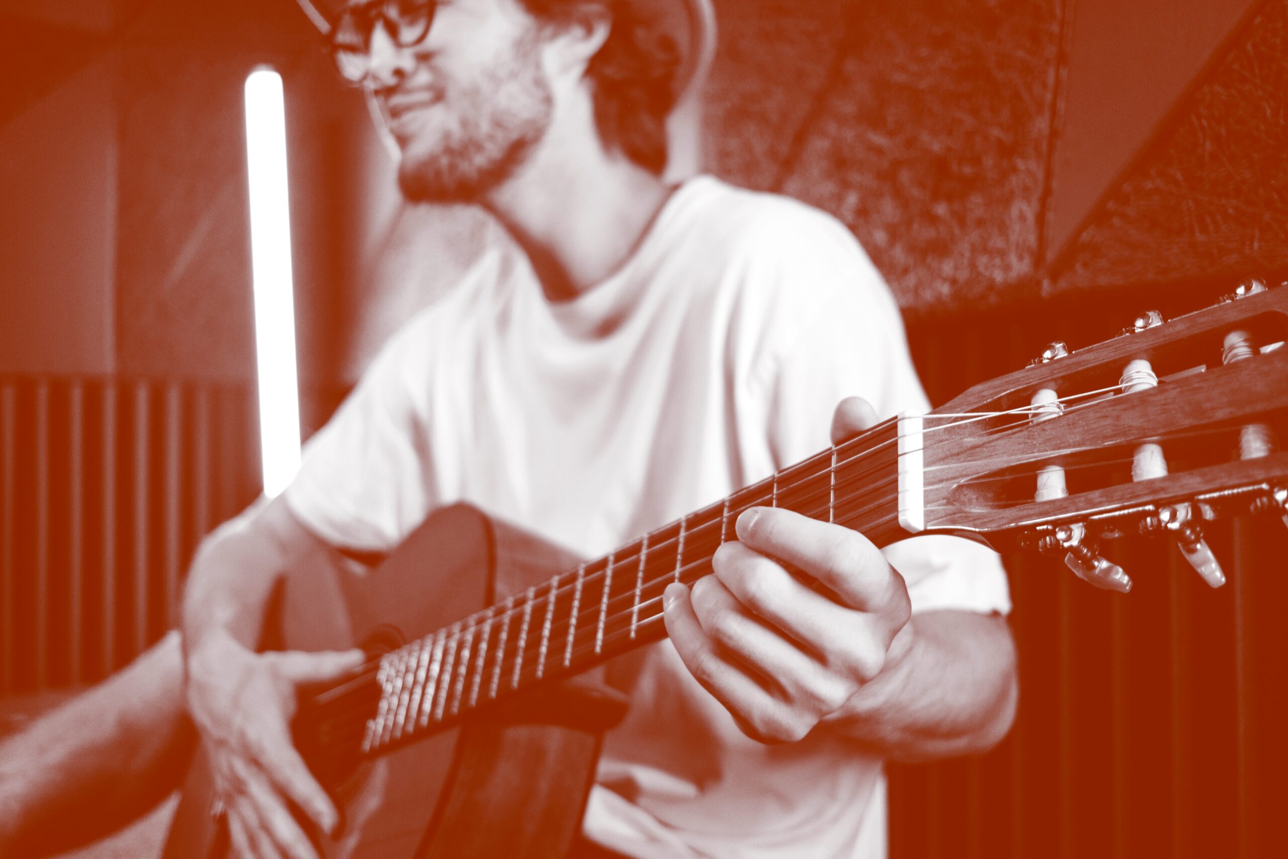 Close up young attractive male musician confidently playing on guitar in modern recording studio