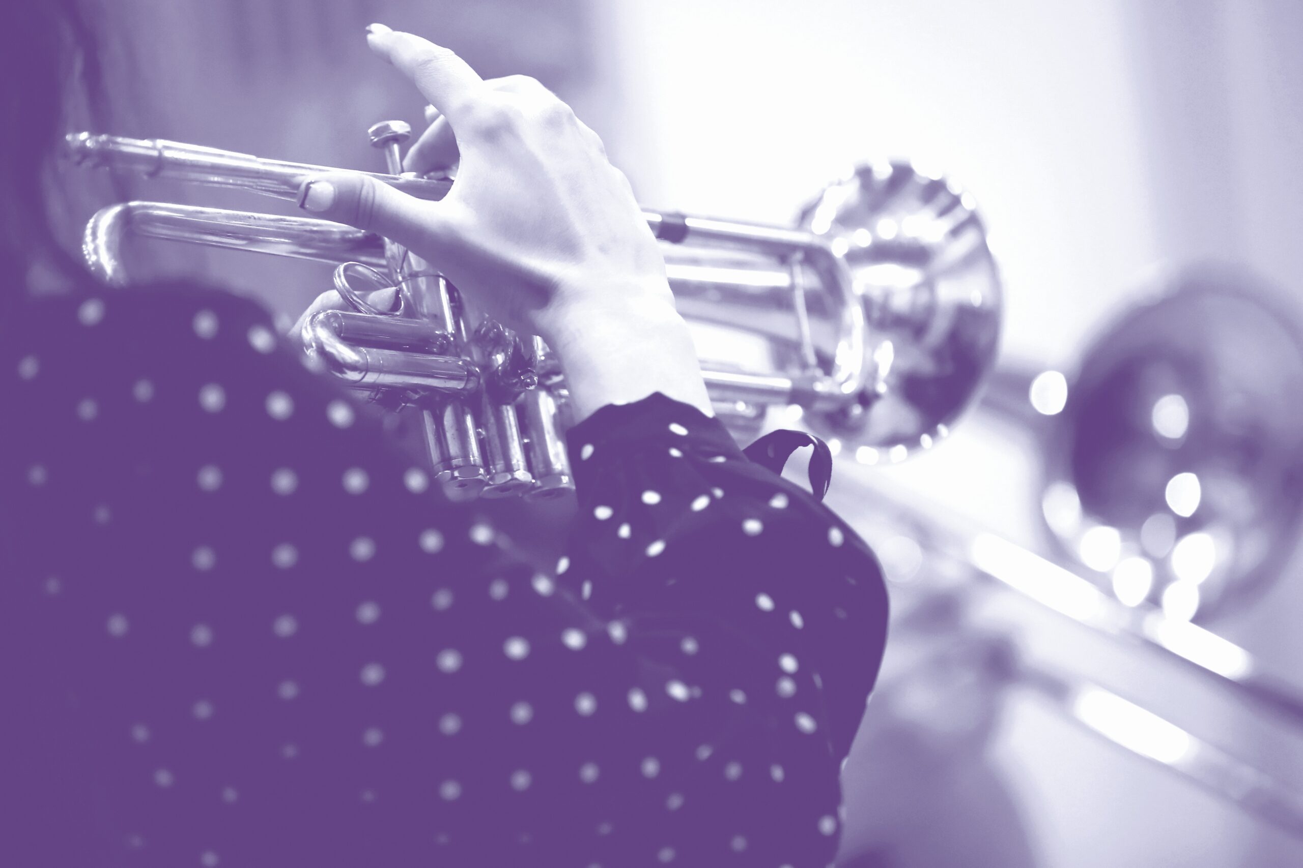 Hand of a woman holding and playing a musical instrument on a trumpet background image of the creative process close-up