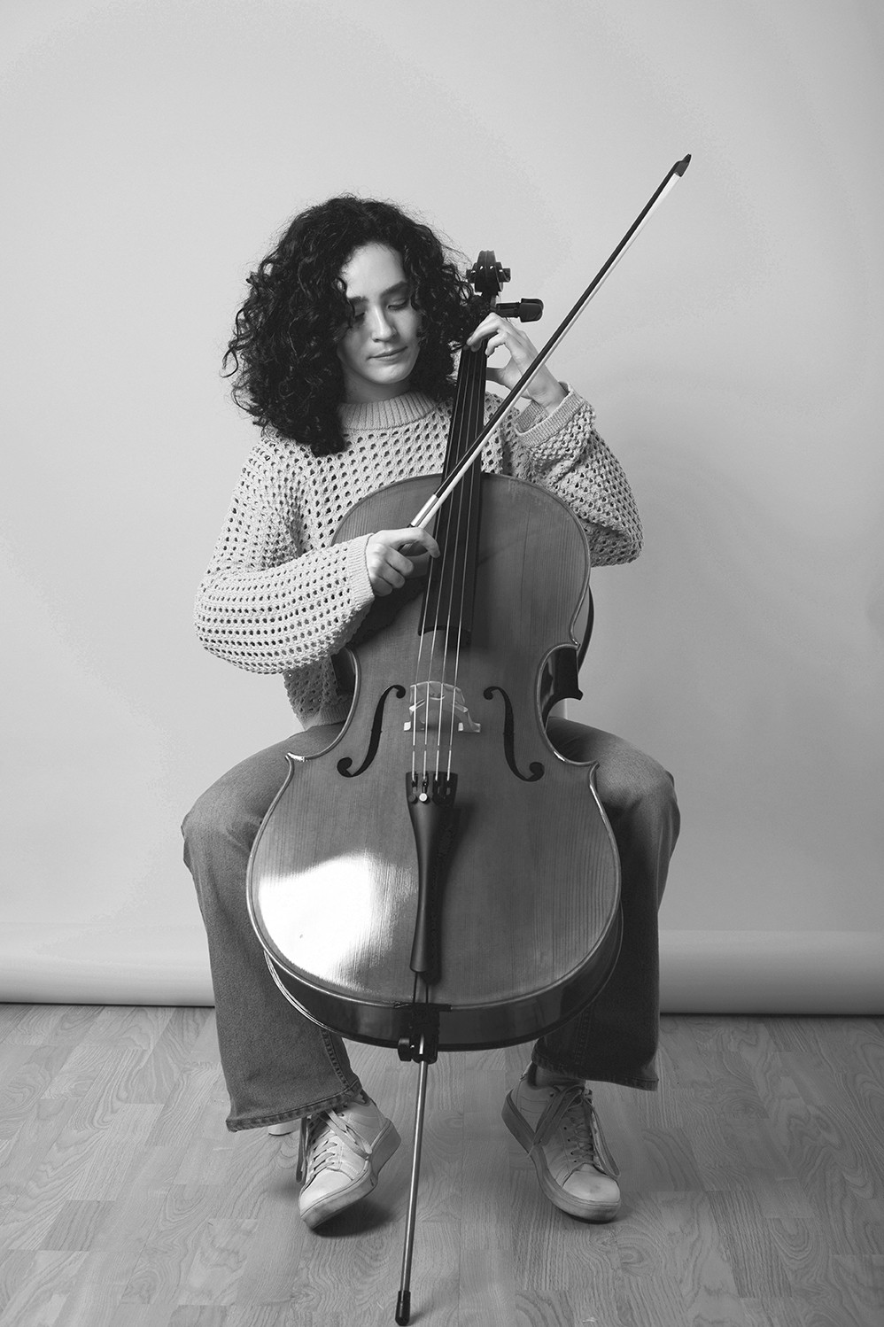 Curly black-haired girl playing the cello in casual clothes